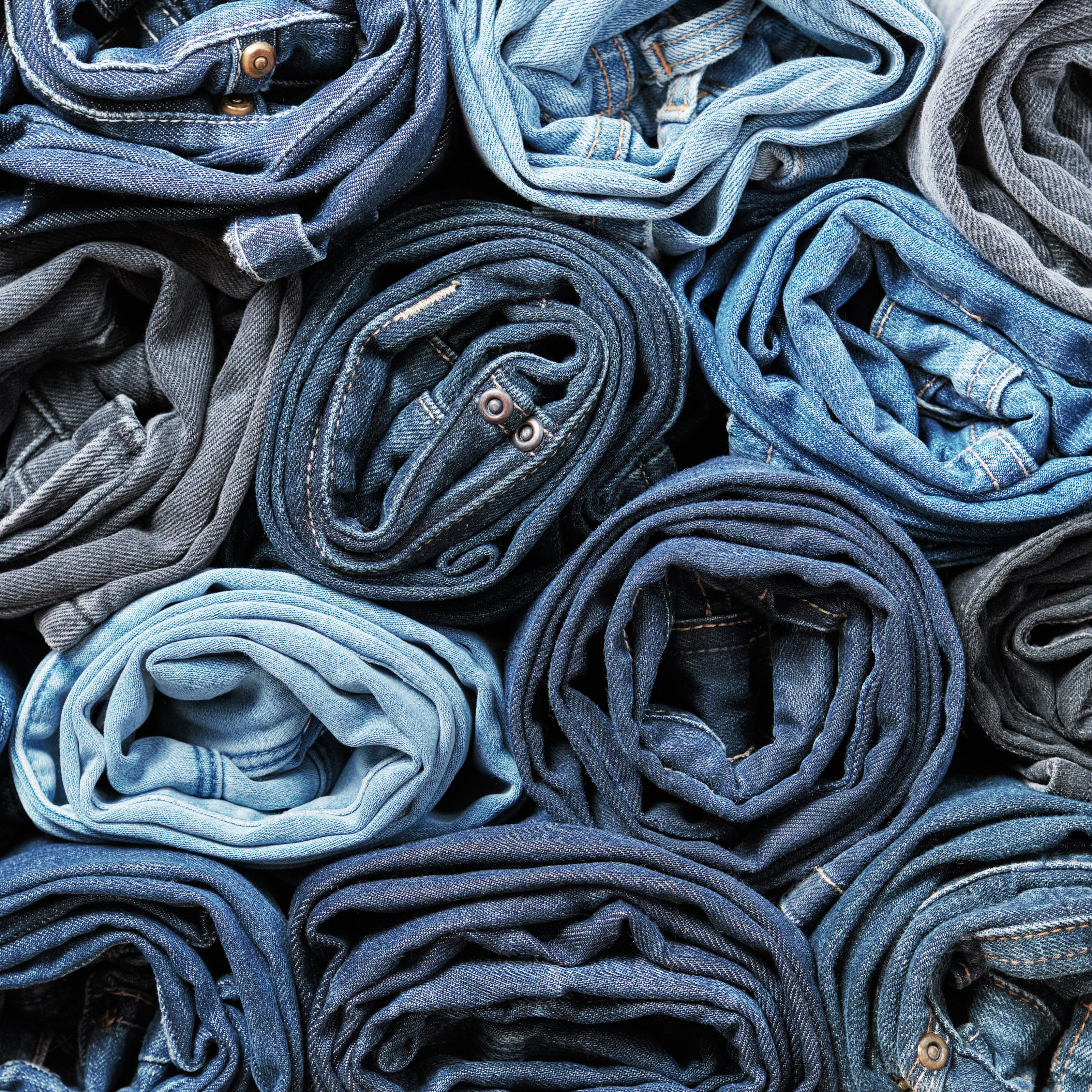 Lots of rolled up jeans. Denim background. Trendy denim clothing, shopping, fashion, consumption.